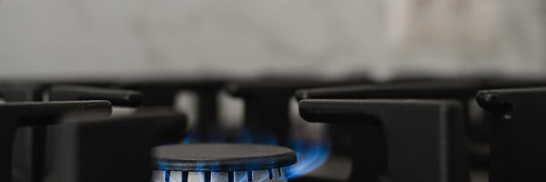 Modern kitchen stove, natural gas burns with a blue flame. Household gas consumption. Close-up, selective focus Modern kitchen stove, natural gas burns with a blue flame. Household gas consumption. Close-up, selective focus